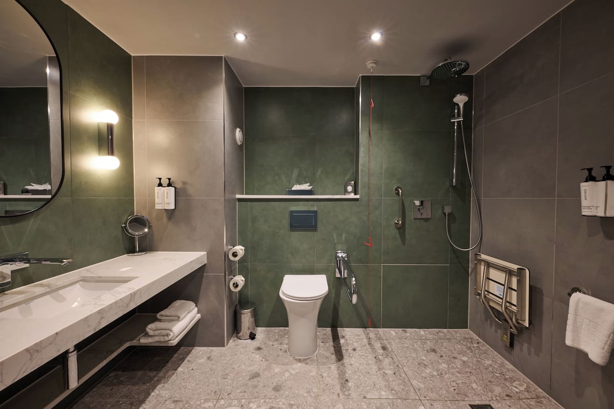 A modern bathroom with a large mirror, a sink, a toilet, and a shower.