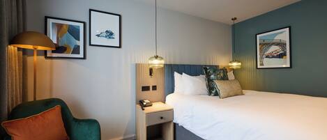 Ein Hotelzimmer mit einem Bett, einem Schreibtisch, einem Sessel und zwei Wandlampen.