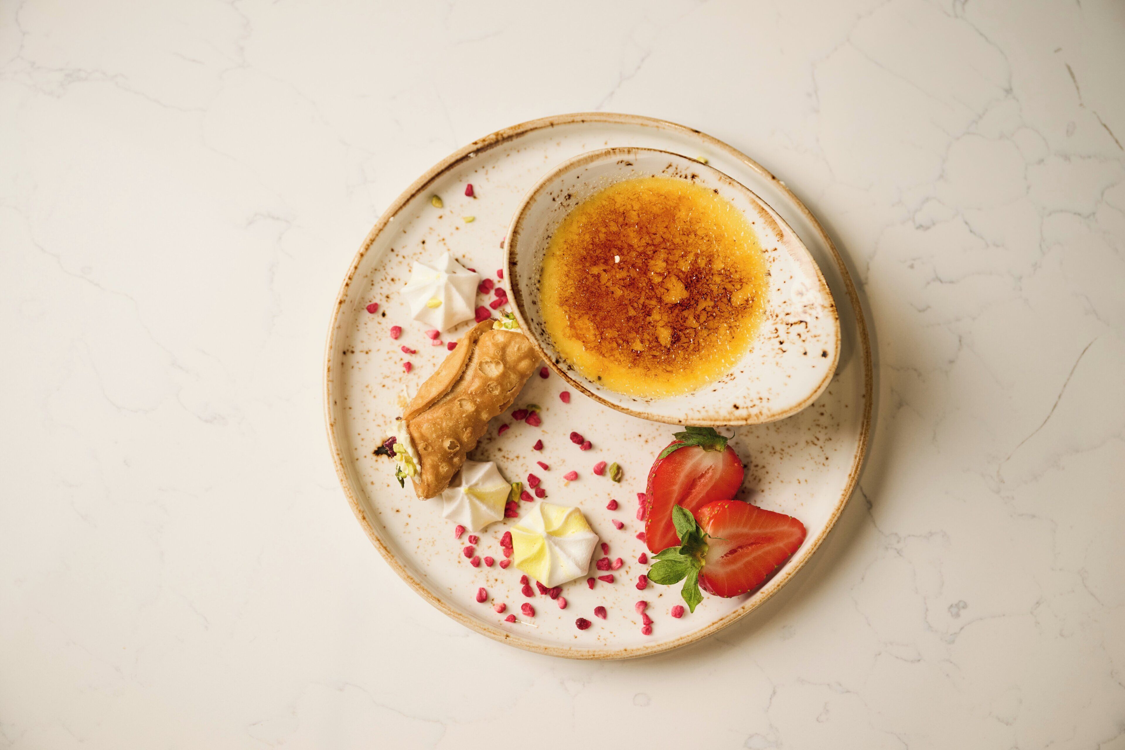 A plate with a dessert, strawberries, and a piece of ginger.