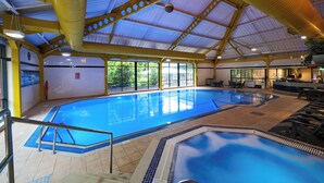 An indoor swimming pool with a high ceiling, yellow beams, and a bar area. - voco Telford - Ironbridge by IHG (Telford)