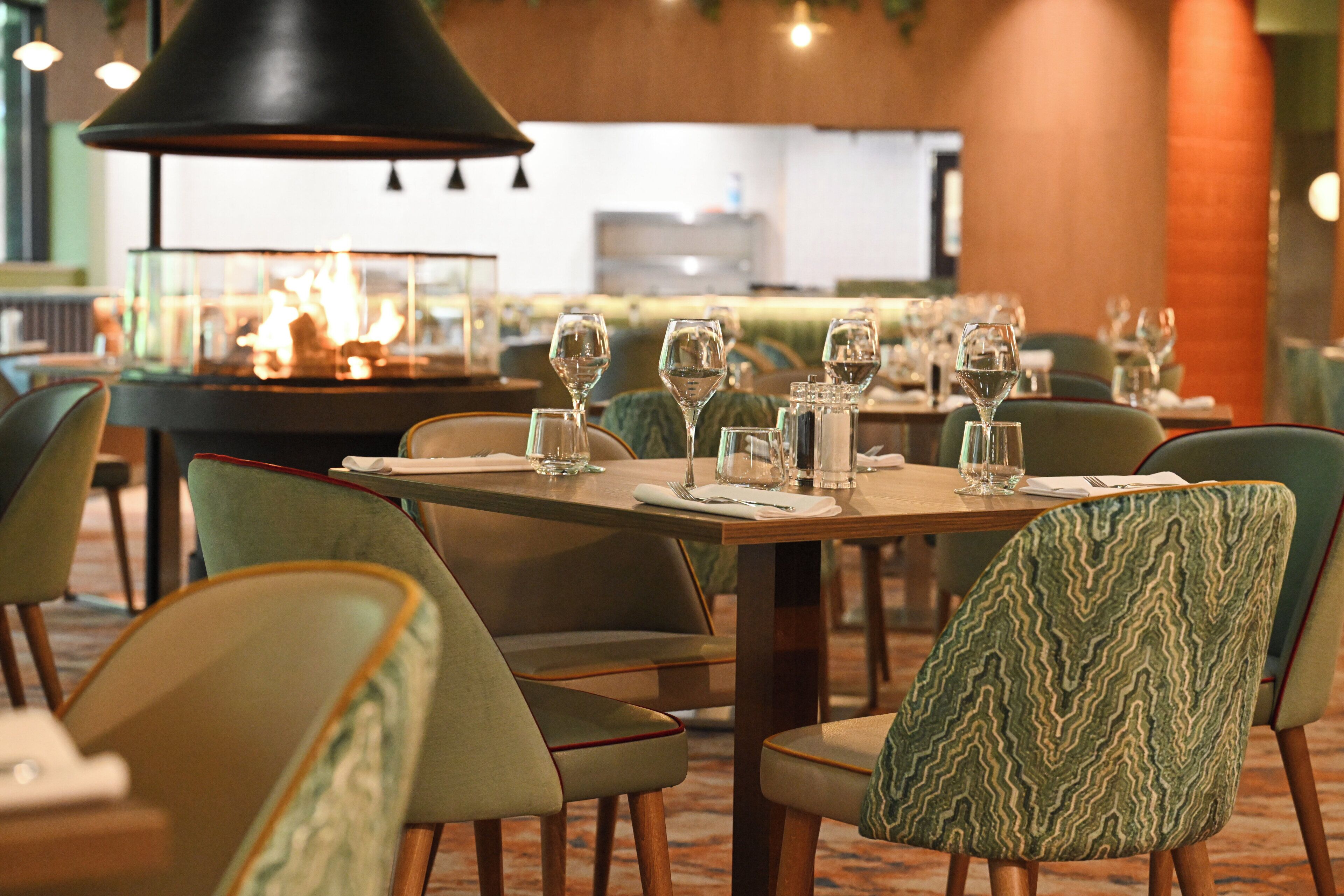 A restaurant with tables set for dining, chairs, and a large hanging light fixture.