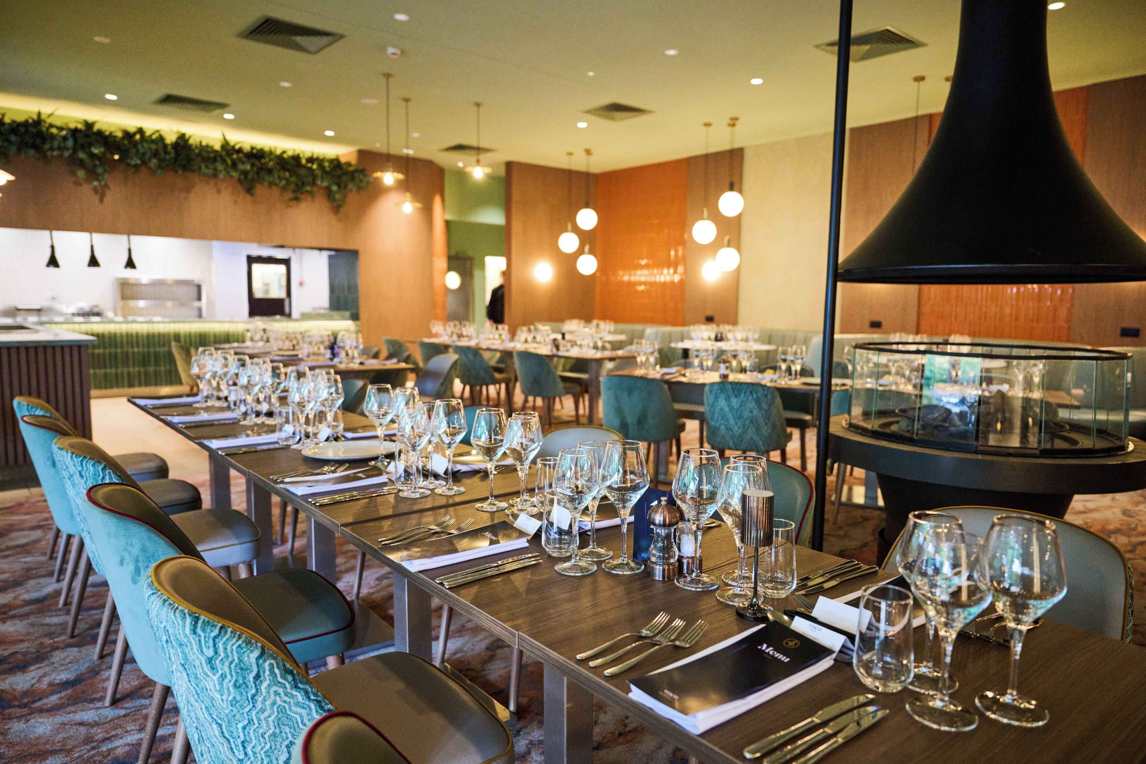 A restaurant with multiple tables set for dining, chairs, and a large black decorative structure.