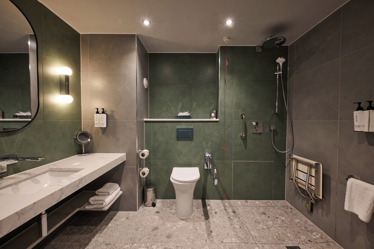 A modern bathroom with a large mirror, a sink, a toilet, and a shower.