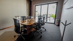 A conference room with a large table, chairs, and a window with a view of greenery.