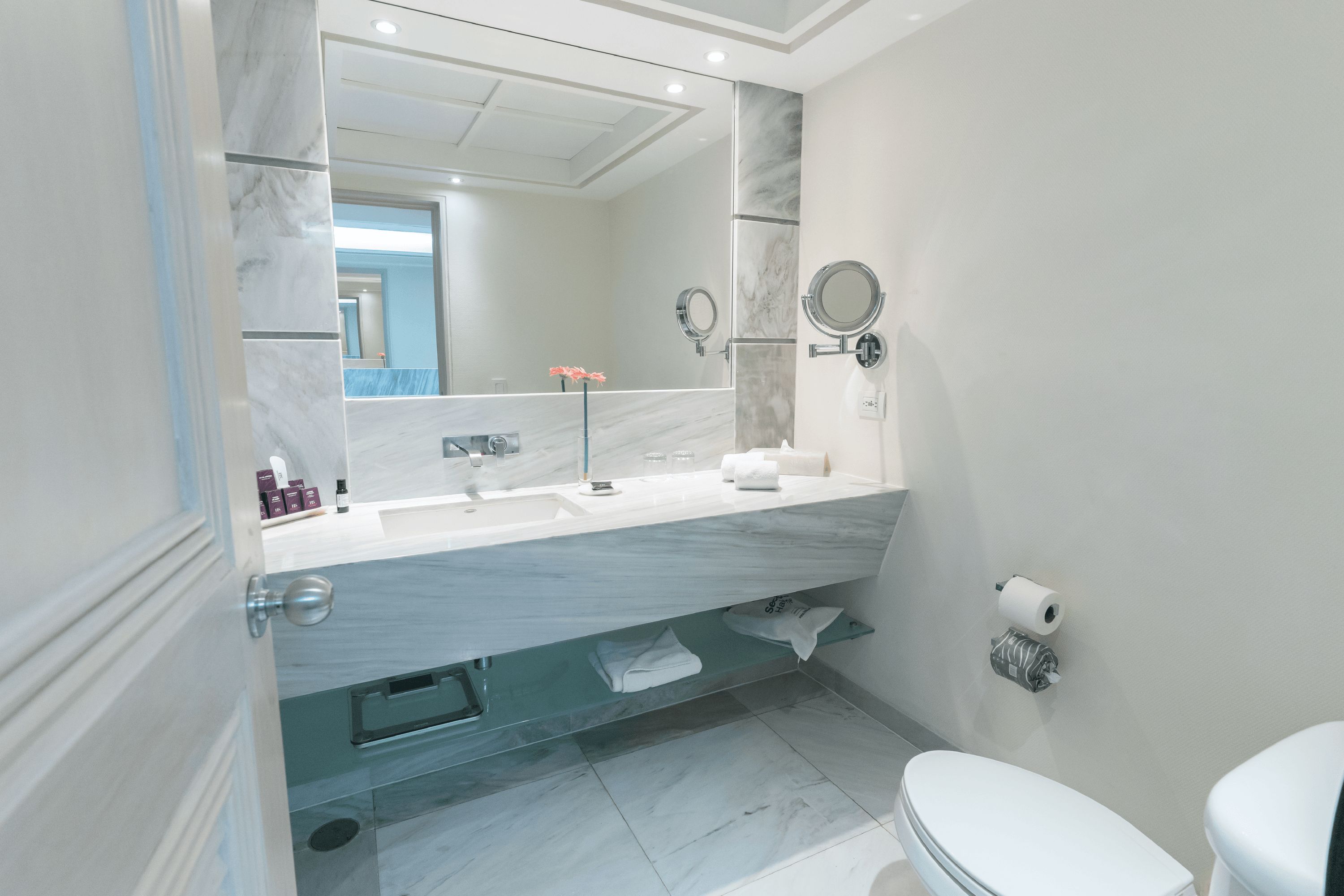 Un baño moderno con tocador de mármol, un espejo grande, un inodoro y una zona de ducha.