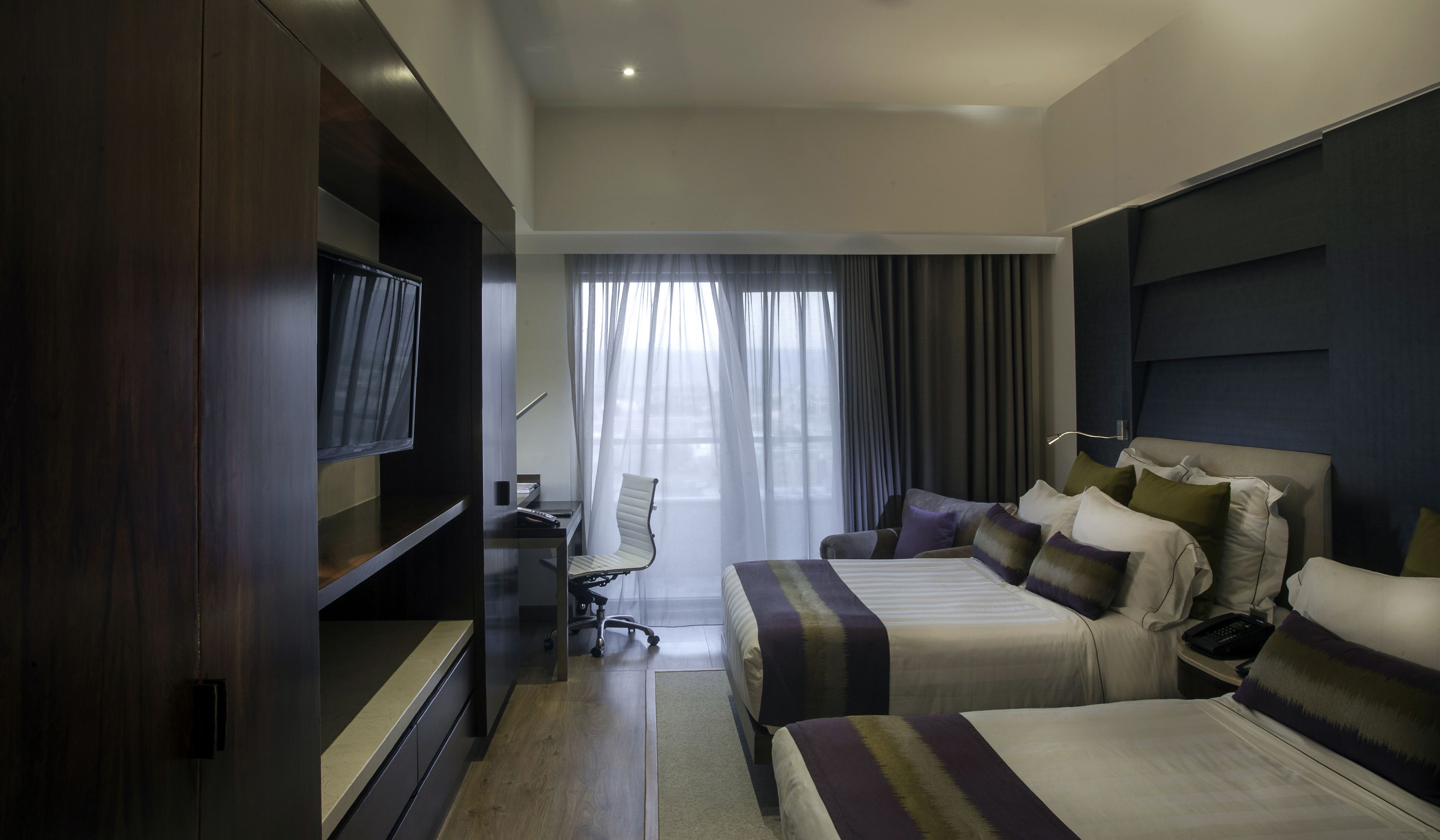 Una habitación de hotel con dos camas, televisión, escritorio y una silla.