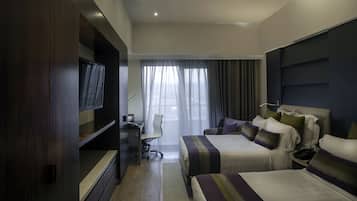Una habitación de hotel con dos camas, televisión, escritorio y una silla.