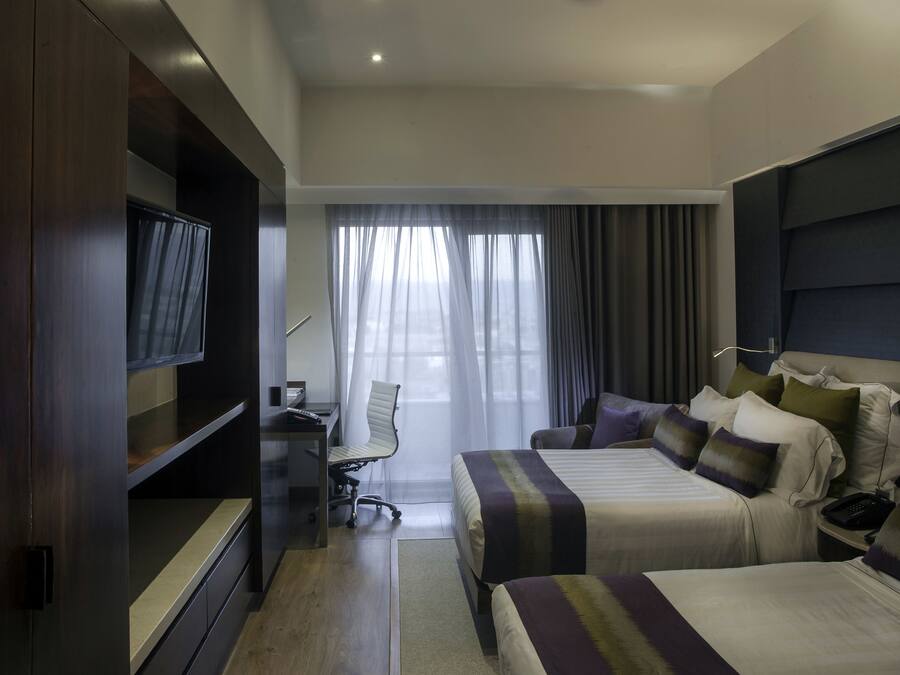 Una habitación de hotel con dos camas, televisión, escritorio y una silla.