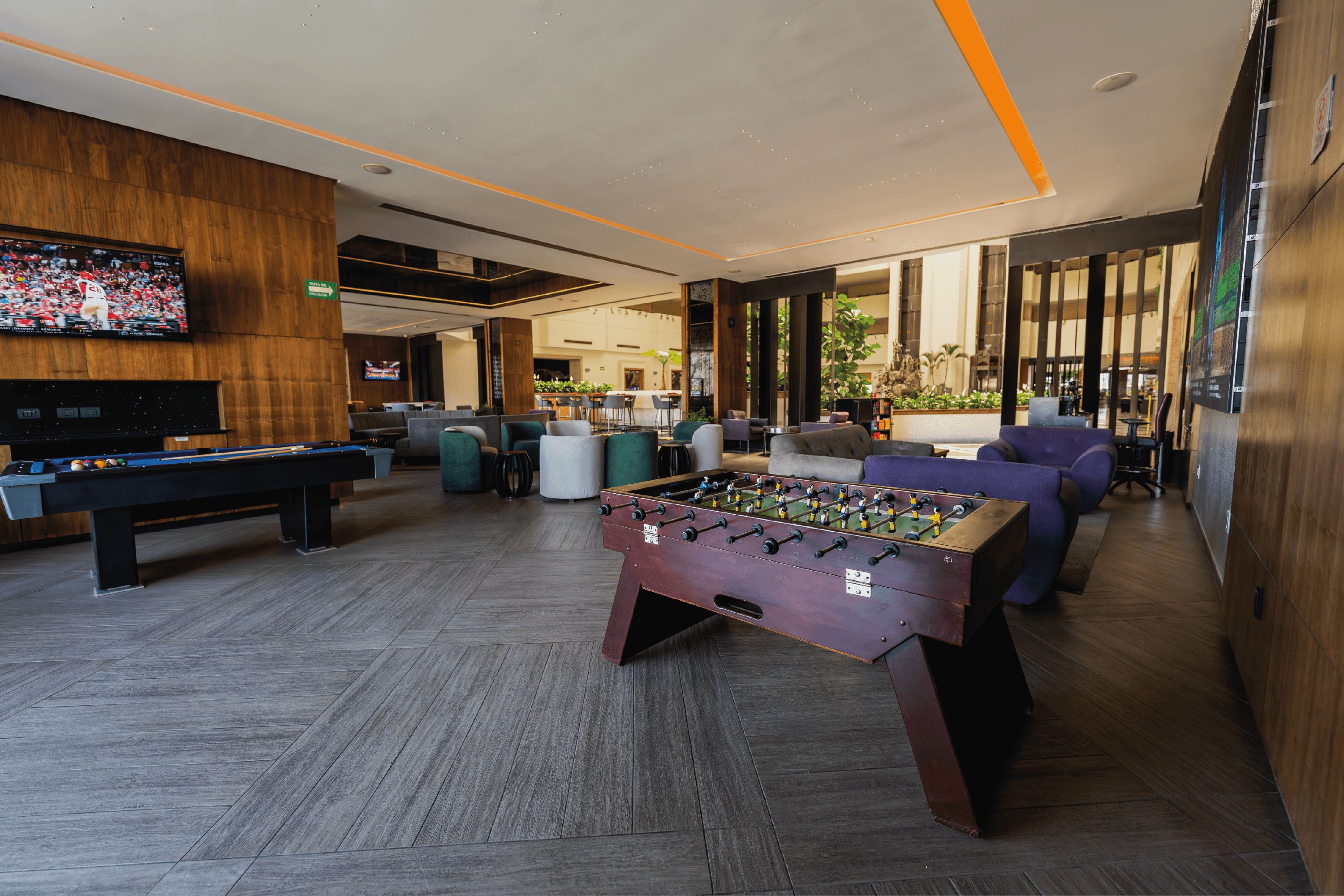 Un área recreativa moderna en el interior, con mesa de futbolín, mesa de billar y asientos cómodos.