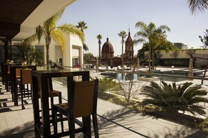 Una piscina al aire libre, sombrillas, sillones reclinables de piscina