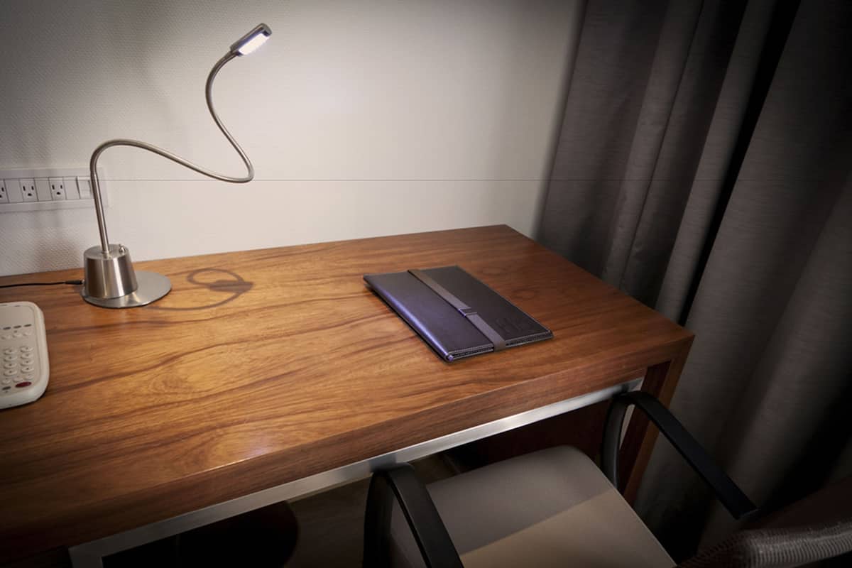 A wooden desk with a laptop, a lamp, and a telephone.