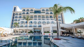 A hotel with a pool area, multiple balconies, and a clear sky.