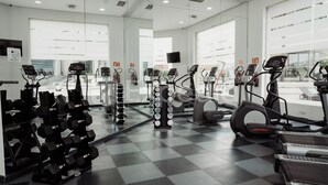A gym with various exercise equipment, including treadmills, elliptical machines, and dumbbells.