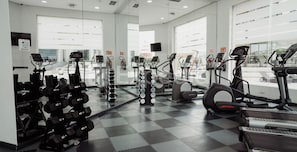 Un gimnasio con diverso equipo de ejercicio, como cintas de correr, elípticas y mancuernas.