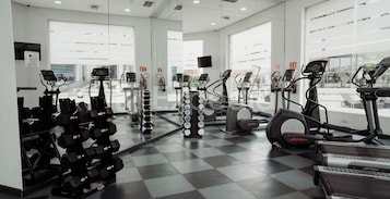 A gym with various exercise equipment, including treadmills, elliptical machines, and dumbbells.