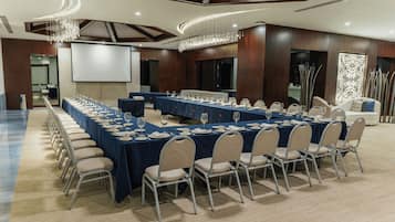 A conference room with a long table, chairs, and a projector screen.