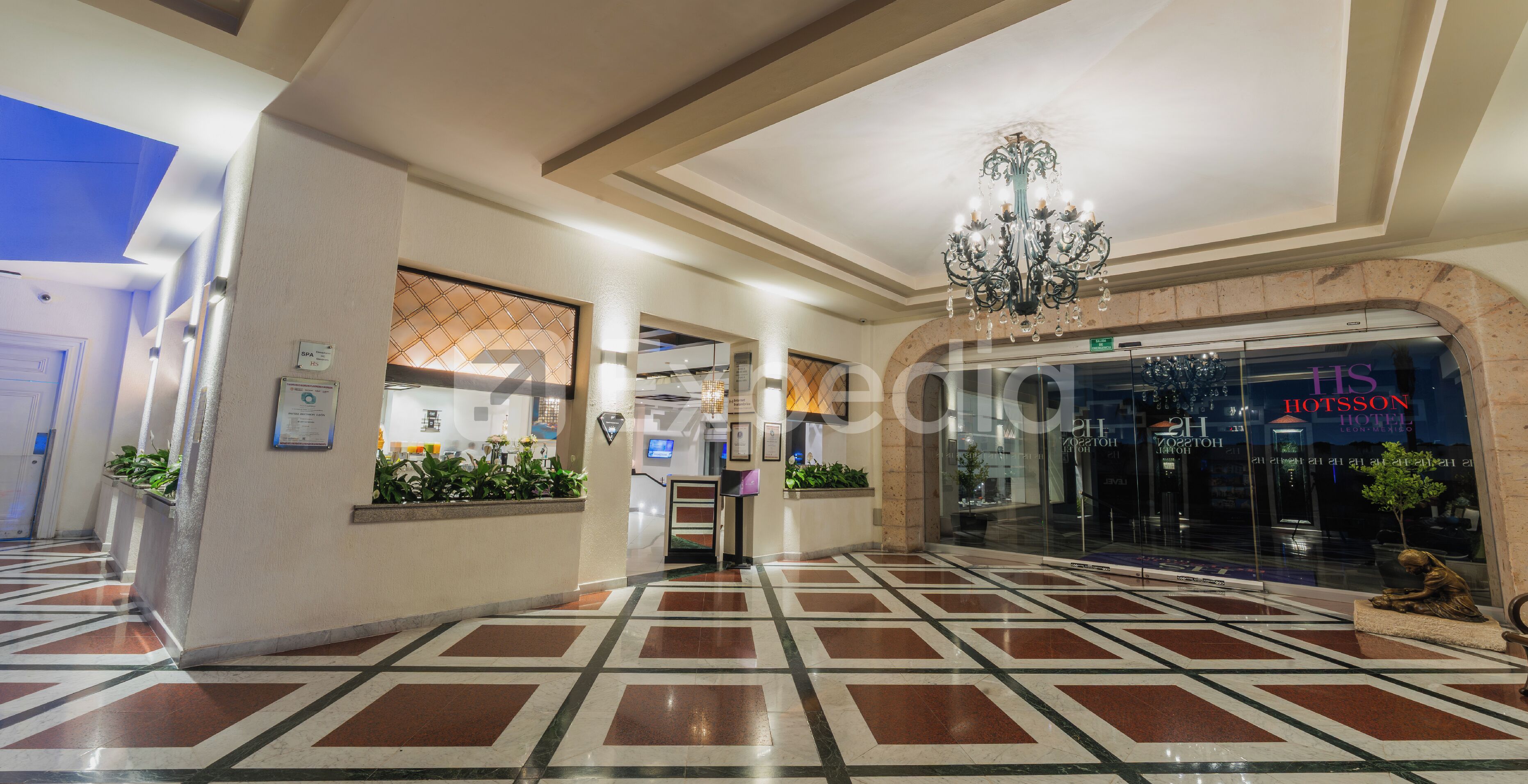 Un vestíbulo de hotel con piso estampado, una araña y una mesa de recepción.