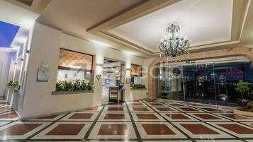 Un vestíbulo de hotel con piso estampado, una araña y una mesa de recepción.
