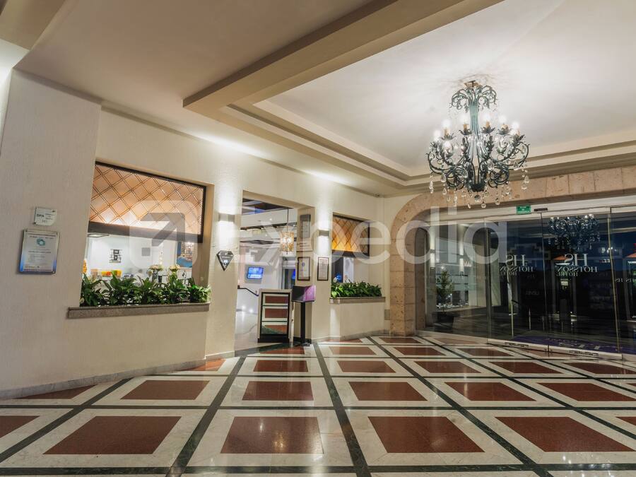Un vestíbulo de hotel con piso estampado, una araña y una mesa de recepción.