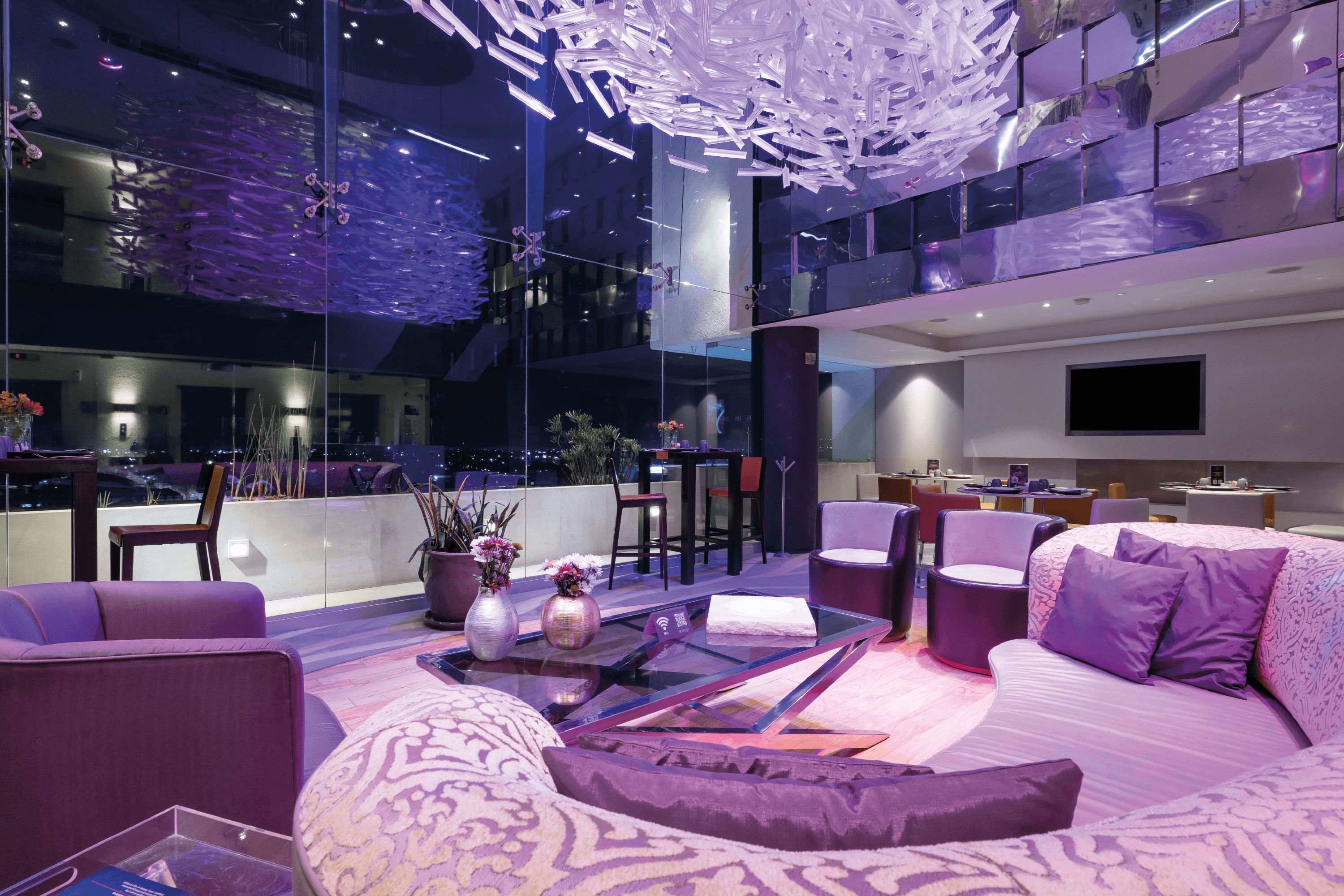 A modern interior with a glass ceiling, a sofa set, and a dining area.