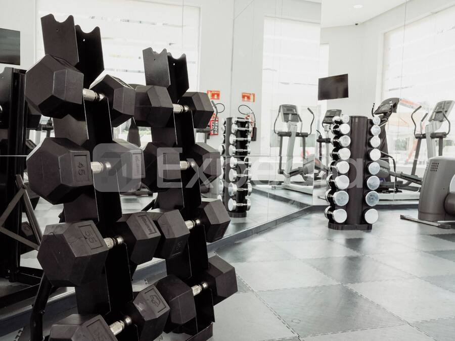 A gym with various exercise equipment including dumbbells, a treadmill, and weight machines.