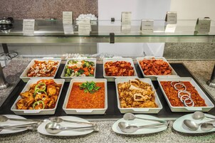 Buffet com diversas opções de comida e utensílios.