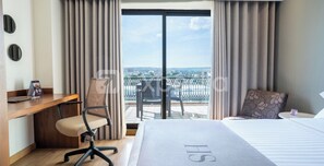 A hotel room with a bed, a desk, a chair, and a balcony with a city view. - HS HOTSSON Hotel Leon (León)