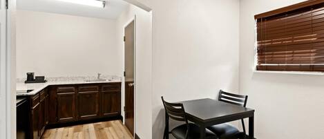 A compact kitchen with wooden cabinets, a countertop, and a dining area with a table and chairs.