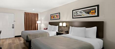 Habitación de hotel con dos camas, una puerta, una cortina y dos lámparas fijadas a la pared.