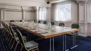 A conference room with a long table, chairs, and a large window with curtains. - Sunday Hotel Garmisch Partenkirchen (Garmisch-Partenkirchen)