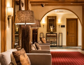 Un vestíbulo de hotel con alfombra roja, muebles de madera y una lámpara grande.