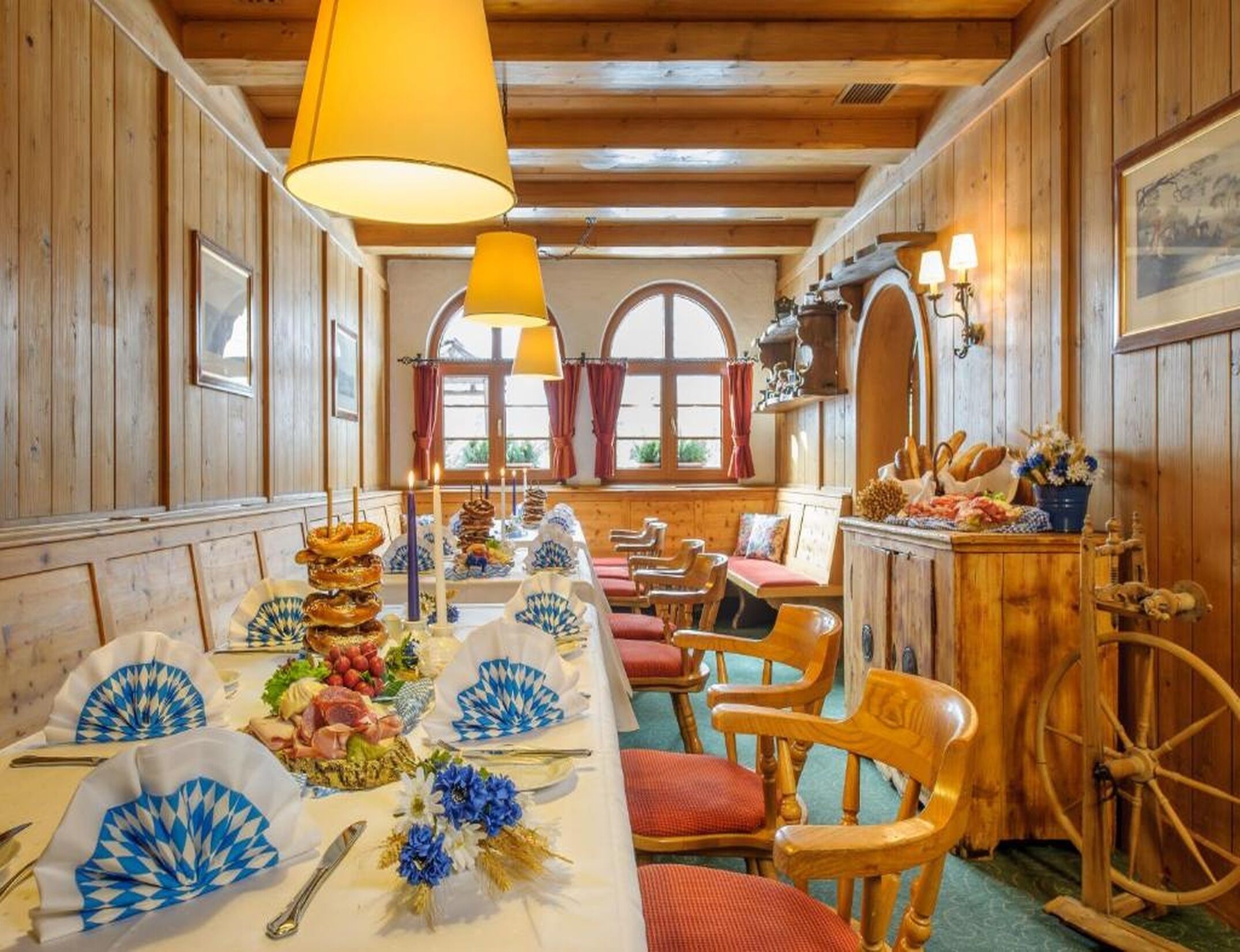 Un comedor con paredes de madera, una mesa larga dispuesta con platos, cubiertos y diversos alimentos.
