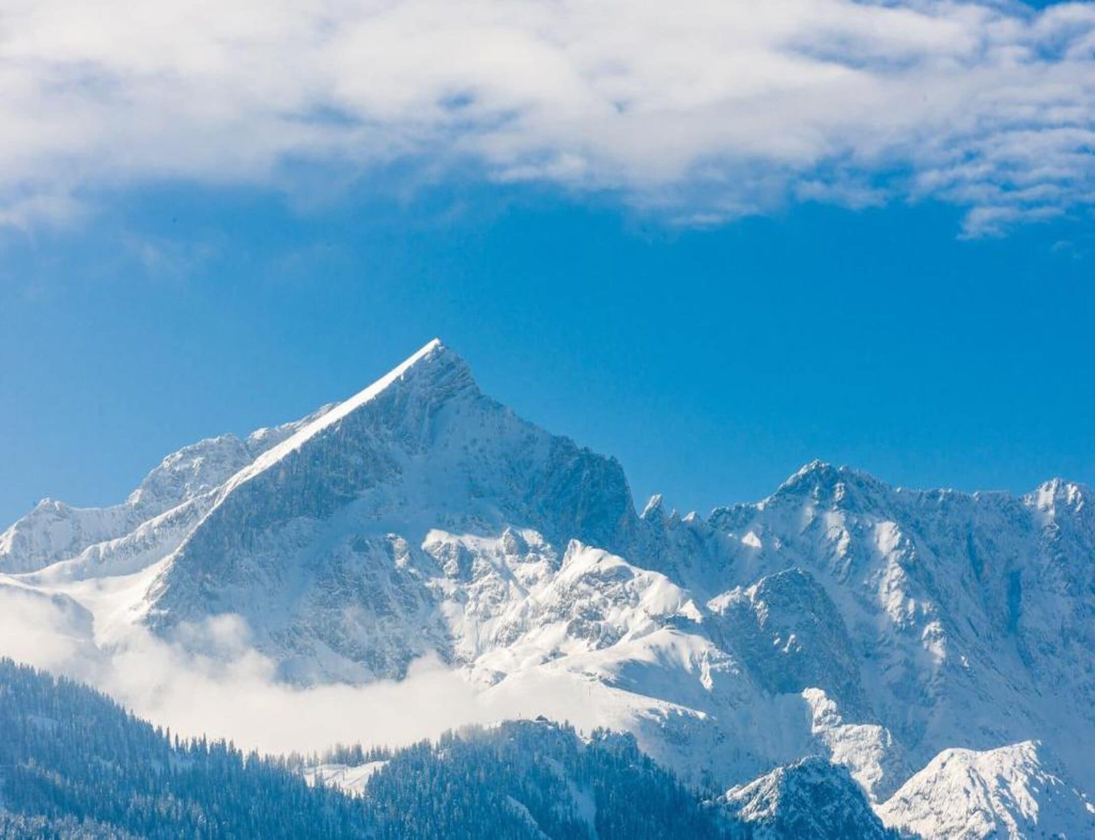 A snow-covered mountain peak with a clear sky.