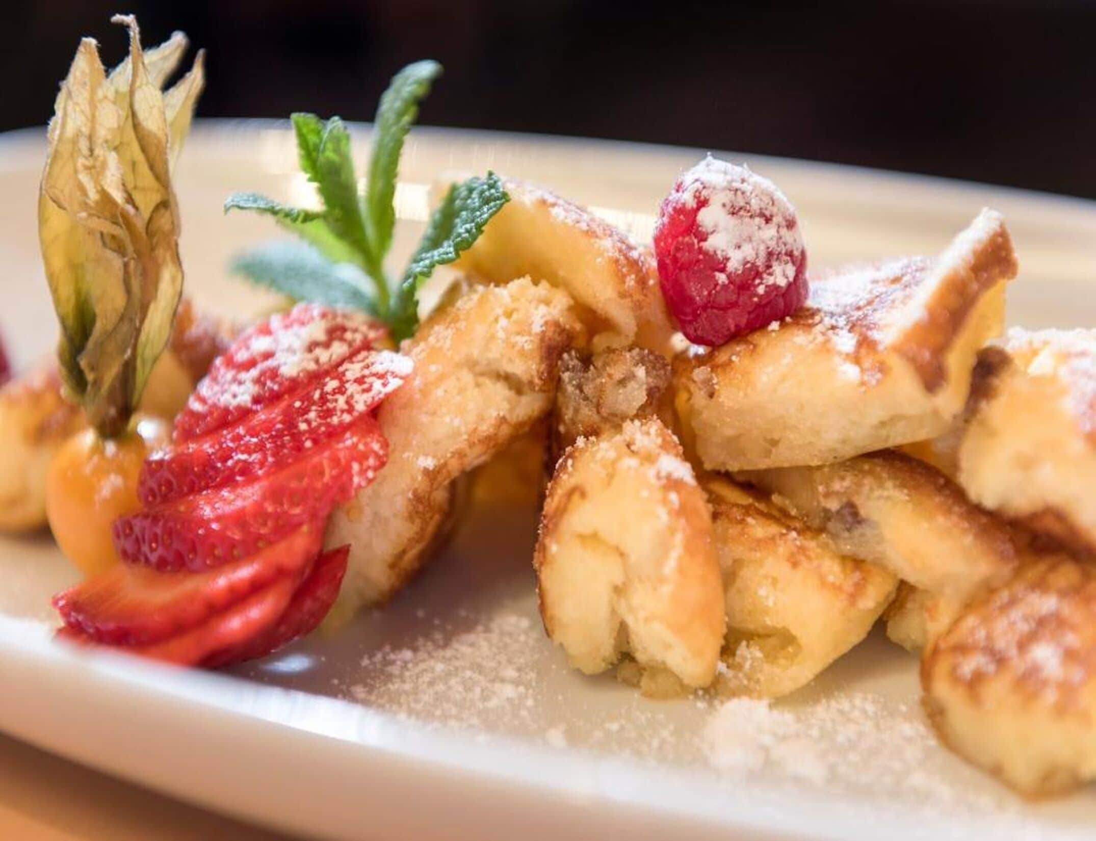 A plate of food with waffles, strawberries, raspberries, and a mint leaf garnish.