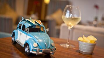 A toy car on a table with a glass of white wine and a bowl of chips.