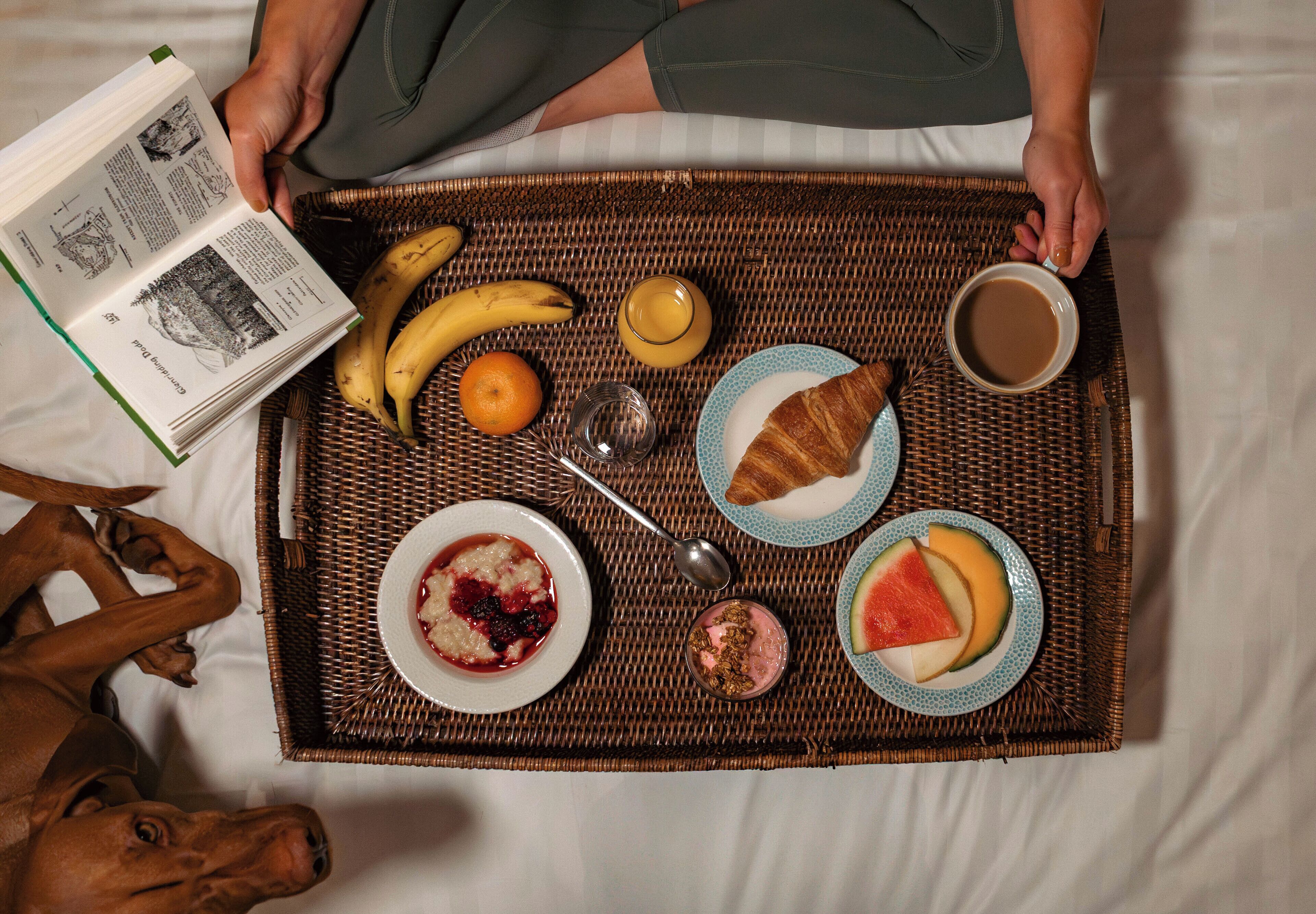 Bandeja de desayuno con comida y bebidas sobre una cama.