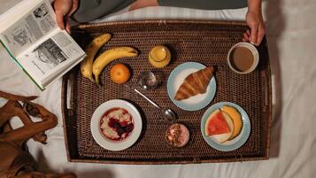 Bandeja de desayuno con comida y bebidas sobre una cama.