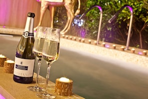A bottle of Prosecco and two glasses of wine on a wooden table near a fountain. - Ambleside Salutation Hotel & Spa (Ambleside)