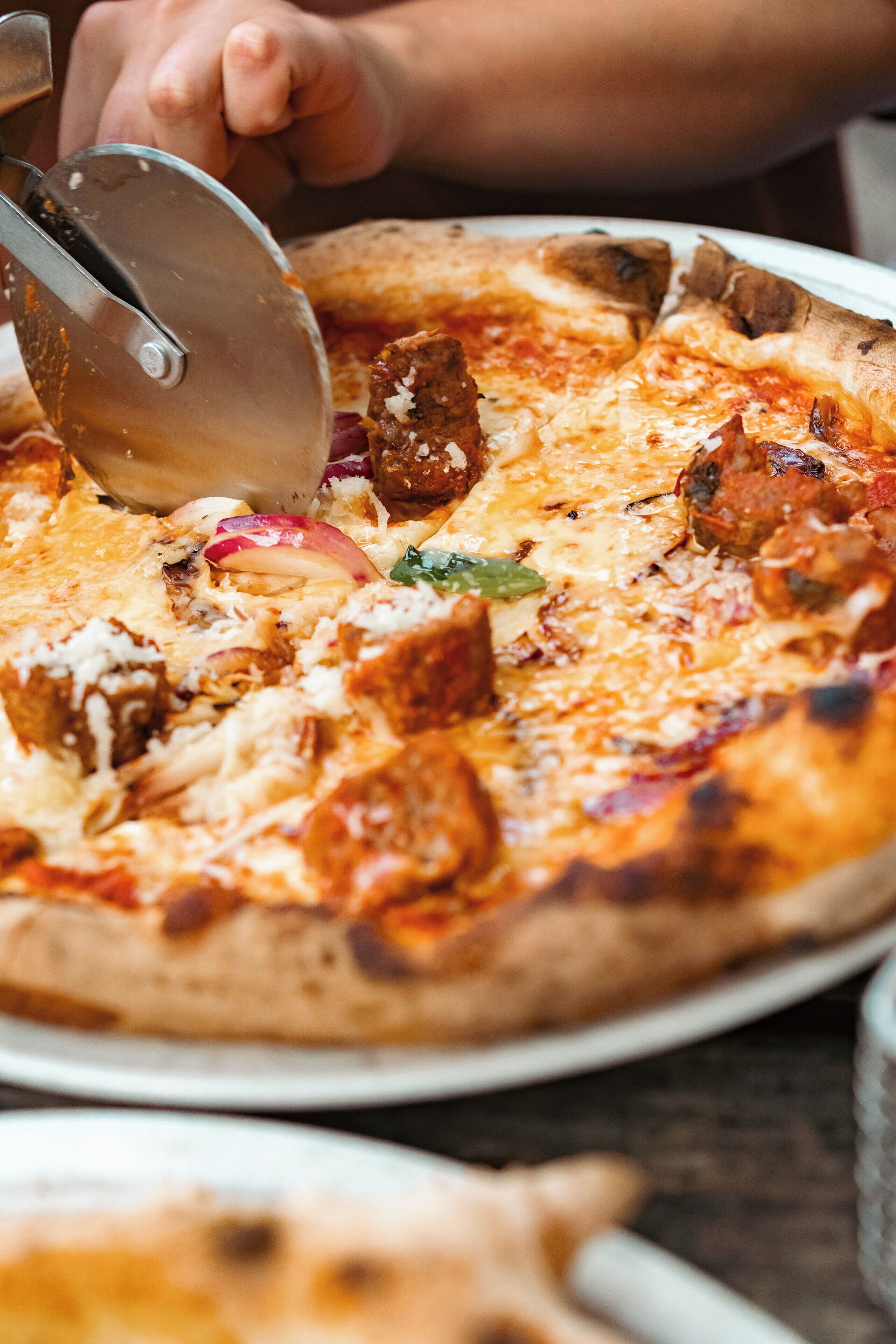 A pizza being cut with a pizza cutter.