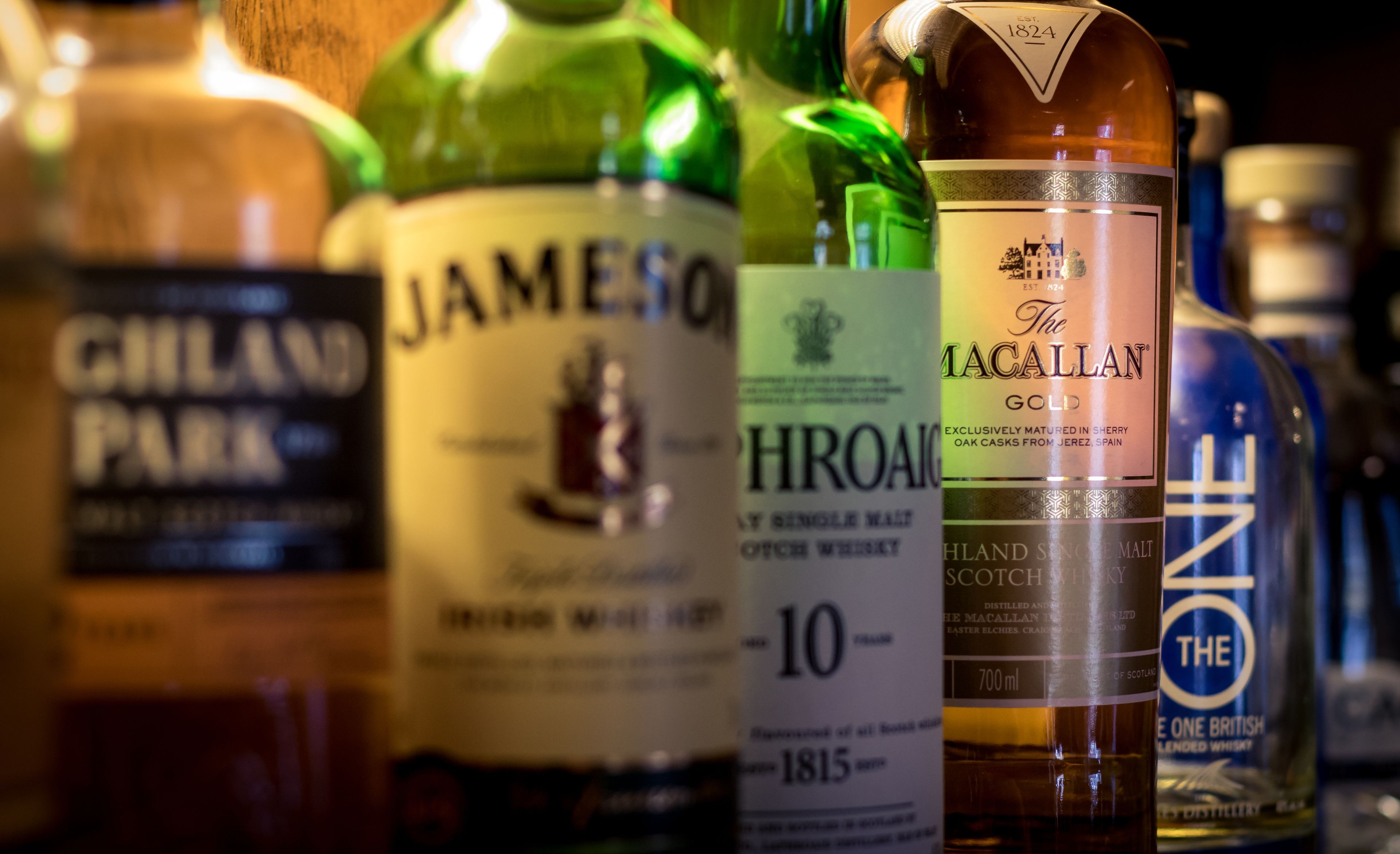 A variety of whiskey bottles with labels, including brands like Jameson and The Macallan.
