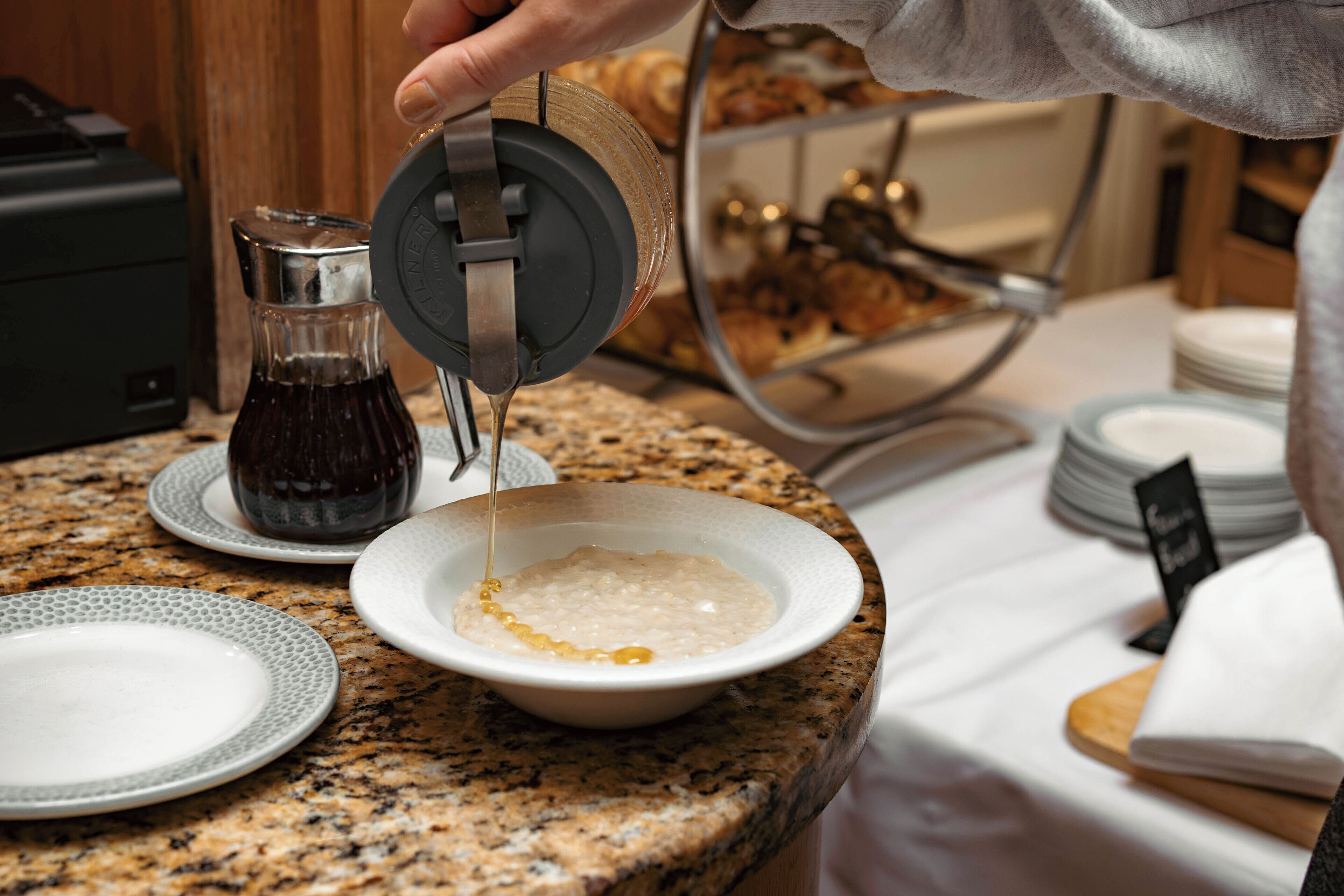 A kitchen counter with a coffee maker, a bowl of cereal, and a plate.
