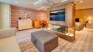 Een moderne woonkamer met een open haard, een grote televisie en een gezellige zithoek.
