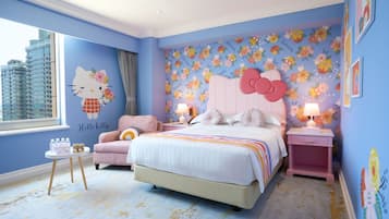Ein Schlafzimmer mit floralem Wandbild, einem Hello Kitty Aufkleber, einem rosa Bett und Blick auf die Stadt.