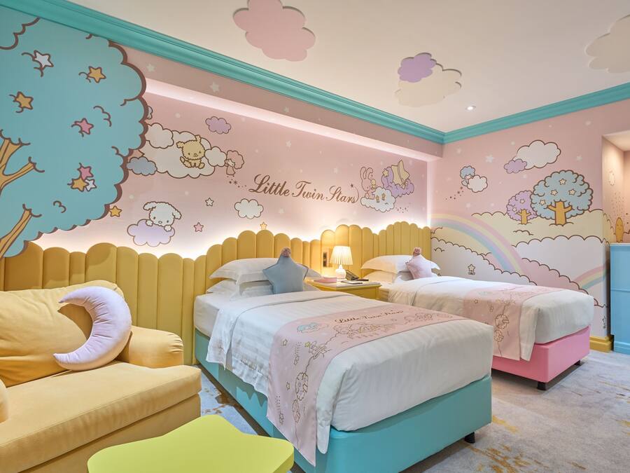 Ein Kinderzimmer mit zwei Betten, einer Schlafcouch und einer Kommode. An den Wänden befindet sich ein Wandbild mit Wolken, Sternen und Bäumen.