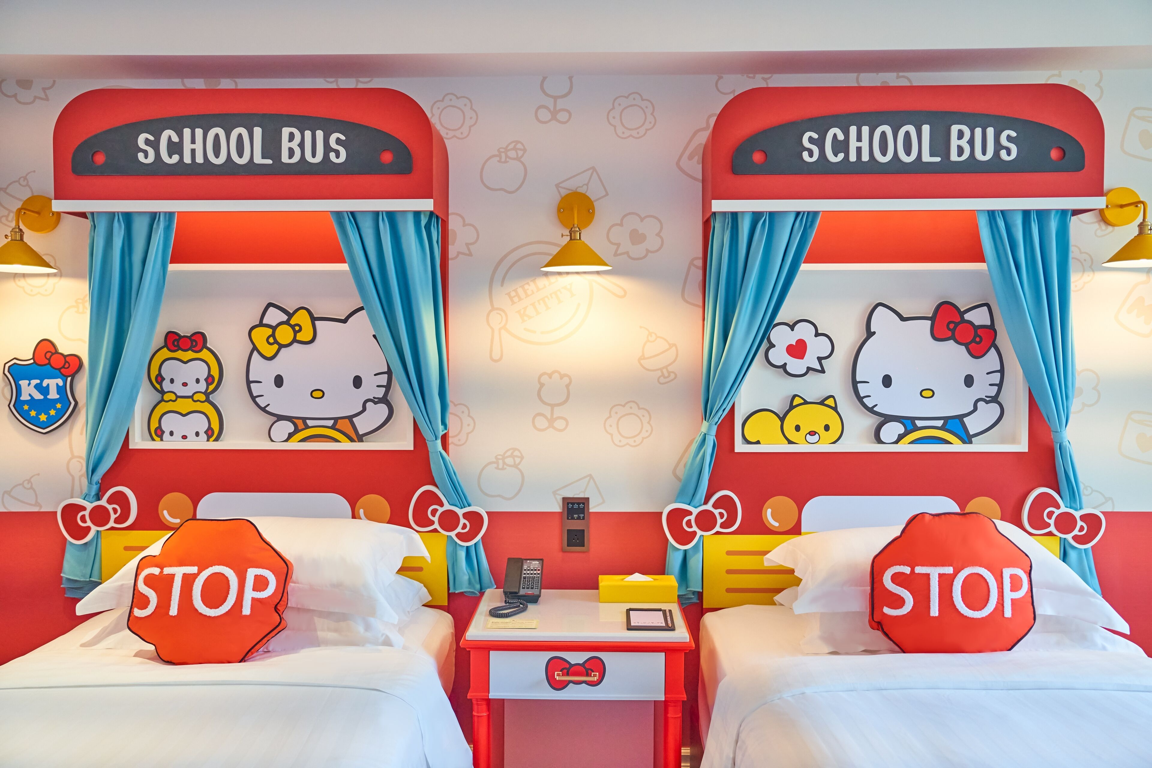 A children's room with two beds, each with a 'Hello Kitty' theme, featuring Hello Kitty decorations and a 'STOP' pillow.