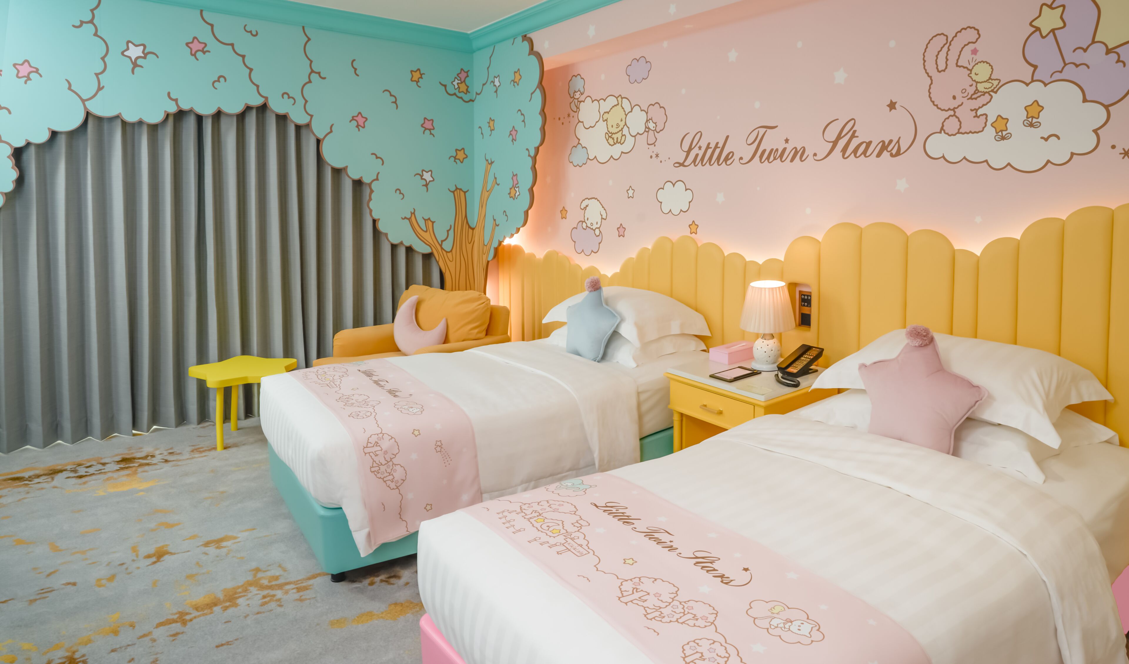 Una habitación infantil con dos camas, una mesita de noche, una pequeña mesa y una cortina.