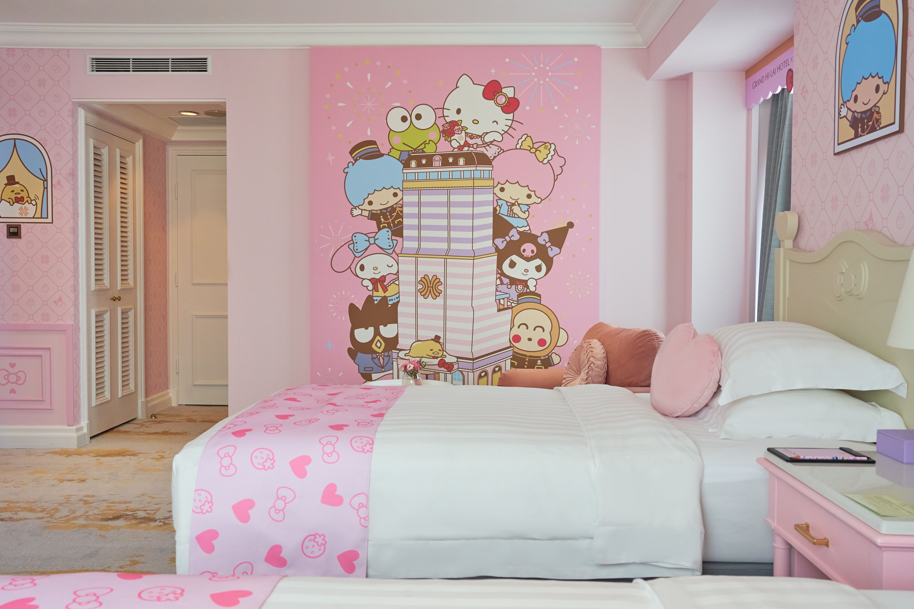 A pink-themed bedroom with a large wall mural, a bed with pink bedding, a nightstand, and a dresser.