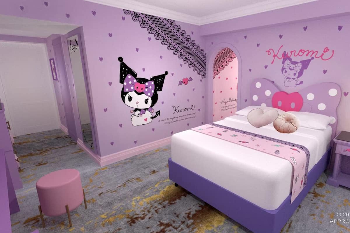 Ein Schlafzimmer in Lila, mit einem Bett mit rosa und weißer Bettdecke, einem Nachttisch mit Lampe und einer Wand, die mit Hello Kitty und Herzchen-Aufklebern verziert ist.