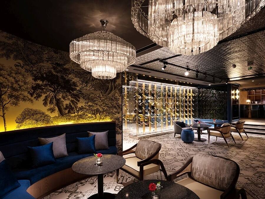 A luxurious lounge area with a sofa, chairs, a round table, and a bar area.
