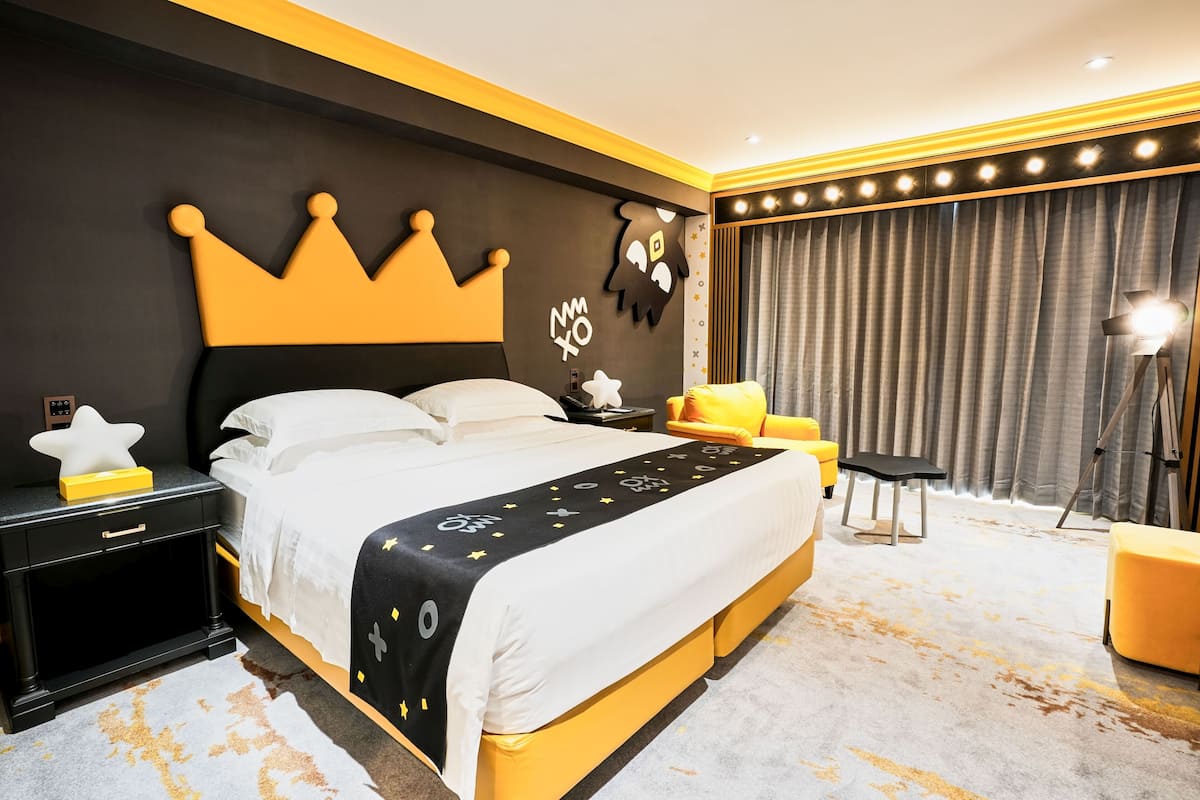 Ein modernes Schlafzimmer mit einem großen Bett, einem Nachttisch, einem Beistelltisch, einem Sessel und einem großen Fenster mit Vorhängen.